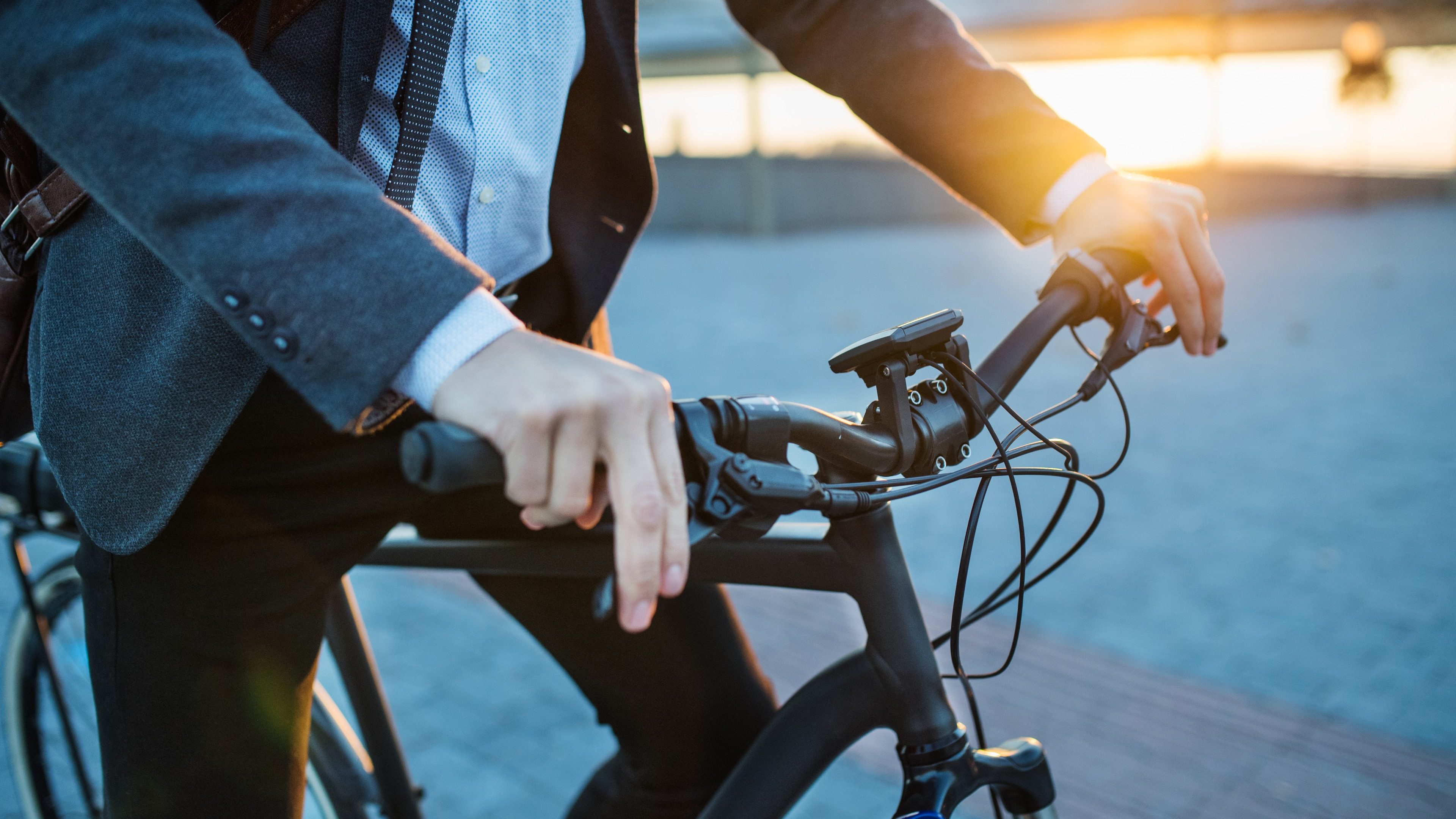 Midsection of businessman commuter with electric bicycle traveling home from work in city.