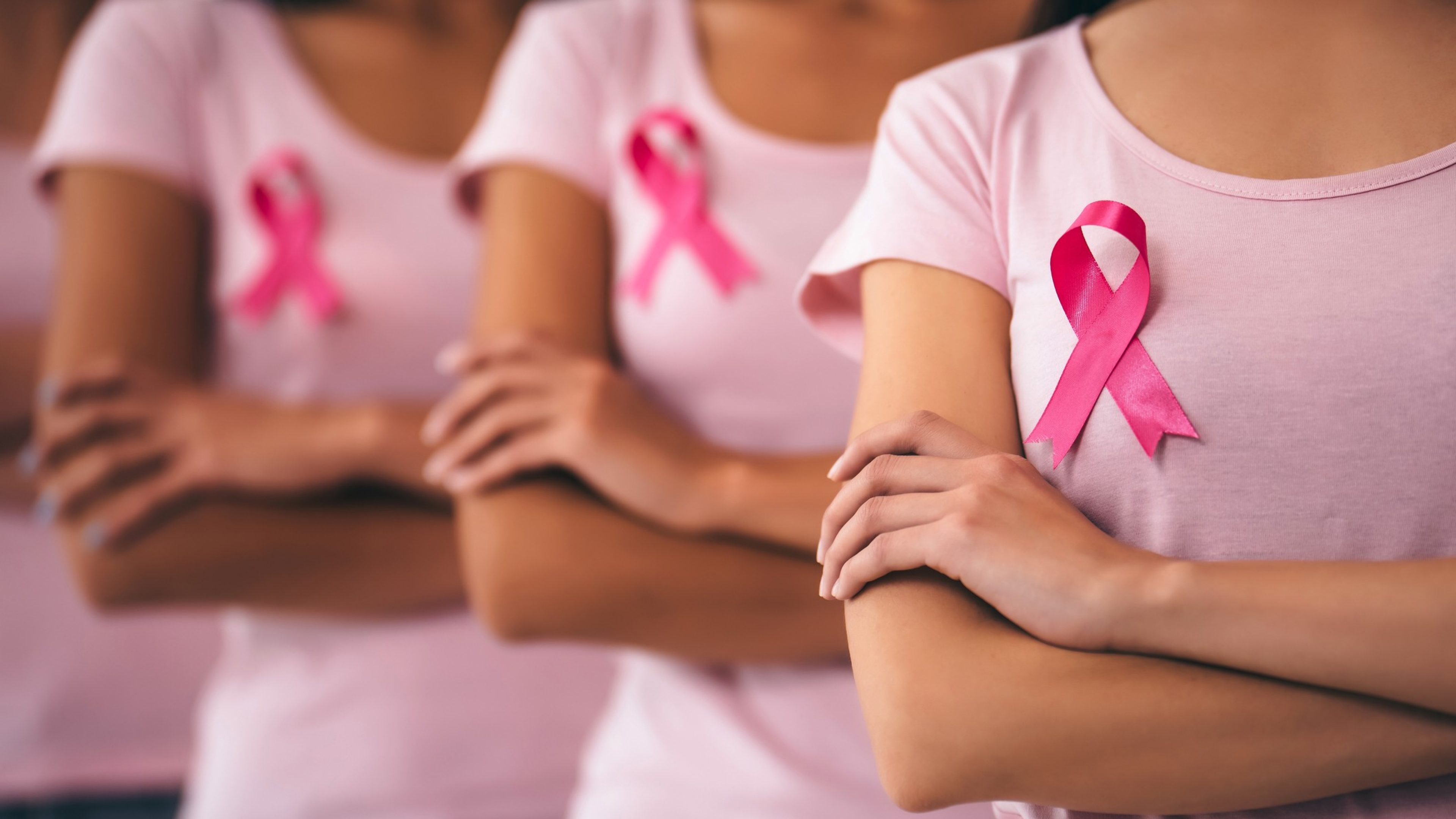 Cropped image of group of young multiracial woman with pink ribbons are struggling against breast cancer. Breast cancer awareness concept.