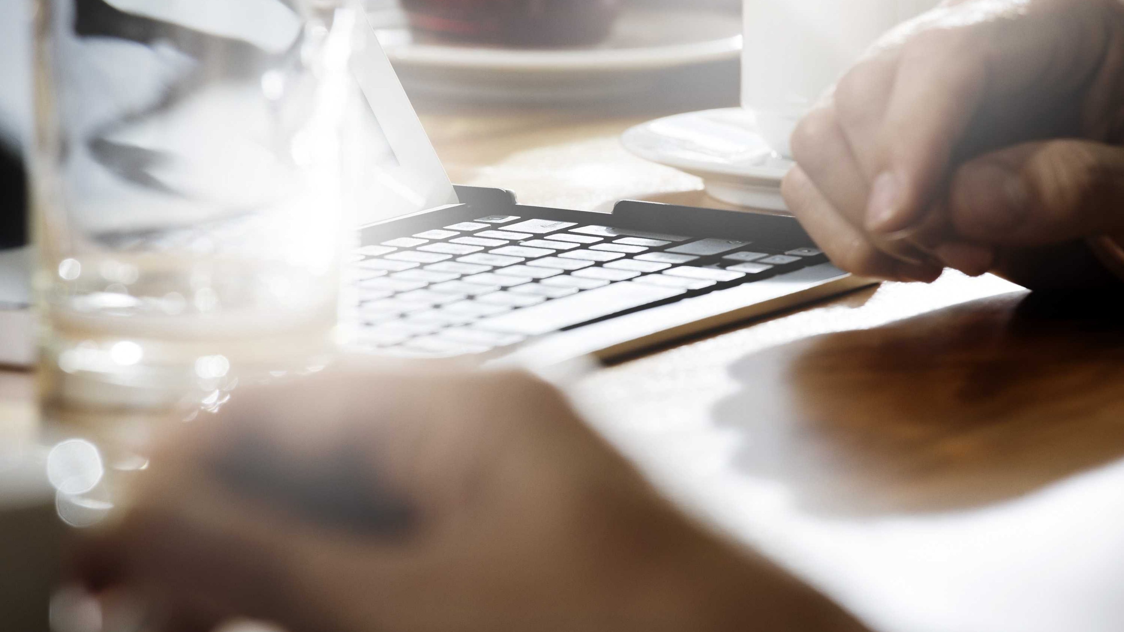Mains frappants sur le clavier d'un ordinateur portable avec un verre d'eau à coté
