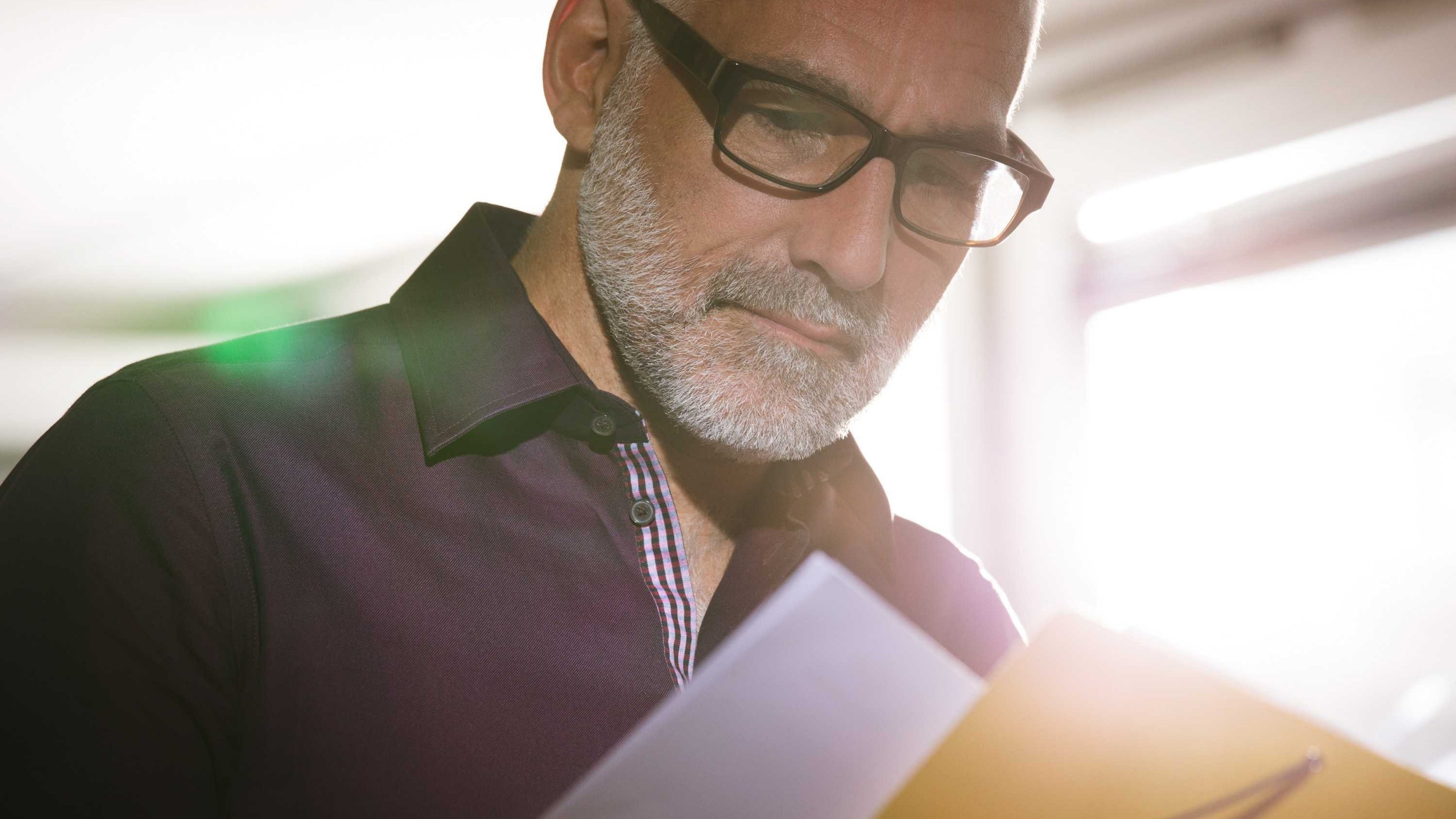 Un homme âgé assis lit un document