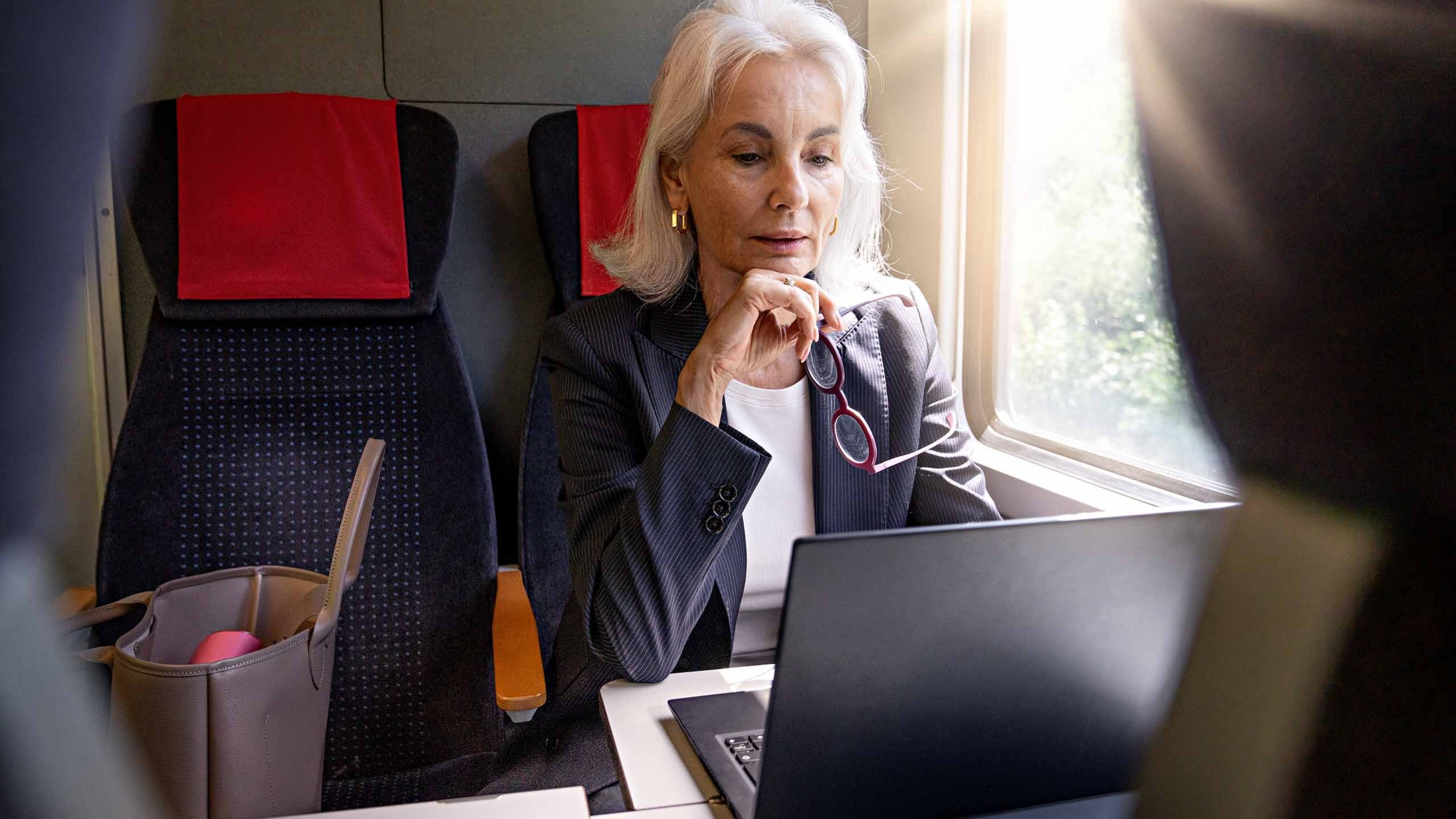 Une femme est assise avec un ordinateur portable dans un train